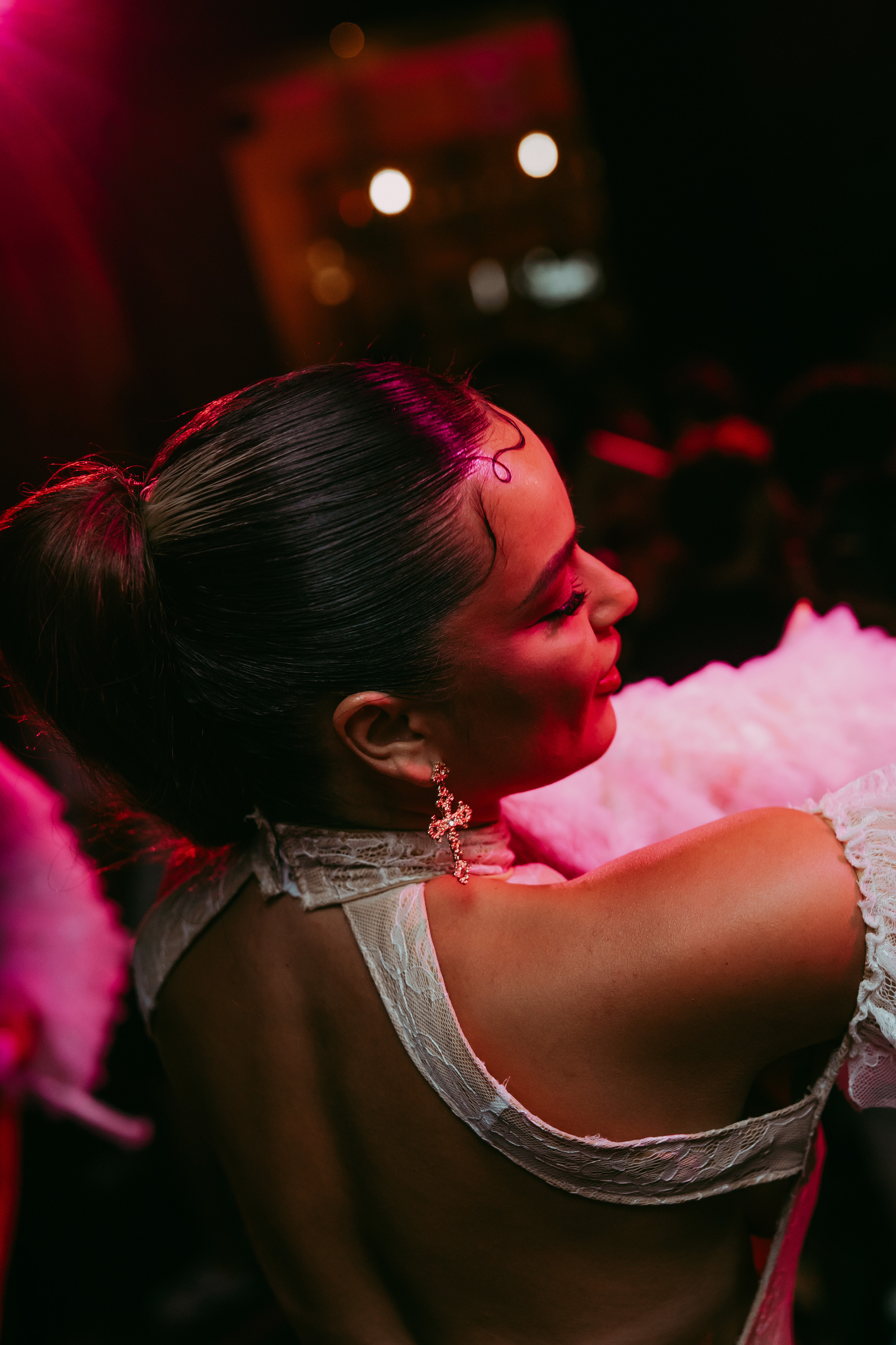 Retrato de perfil de una integrante de Mala Mia bajo luces magenta